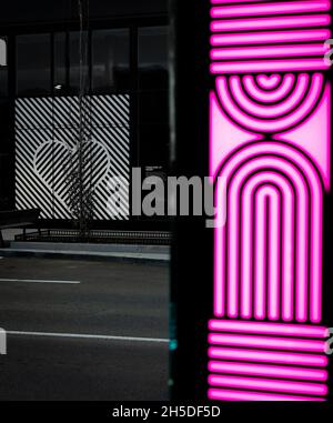 CALGARY, CANADA - Oct 06, 2021: Abstract pink neon lights design with a heart mural in the background at Deerfoot City shopping center Stock Photo