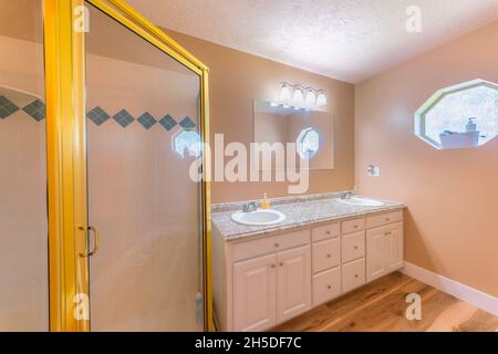 Master bathroom interior with tan walls and toiletries near the hexagon mirror with ornate glass Stock Photo