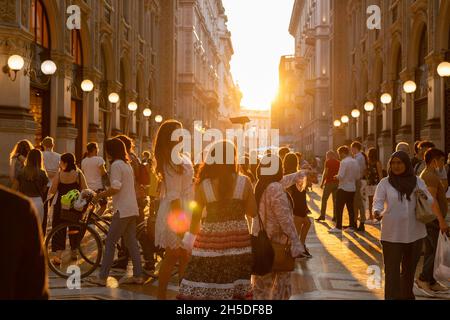 MILANO, ITALY - Sep 10, 2021: Galleria Vittorio Emanuele II in the centre of Milan, Italy. Numerous people in the street. Golden sunlight through the Stock Photo