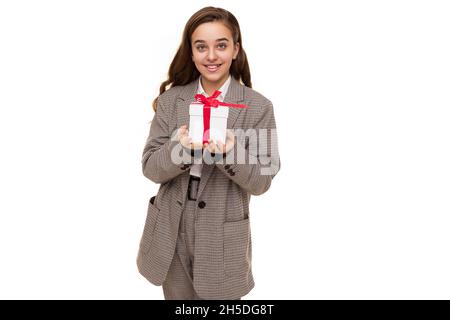 Photo of beautiful cute pretty happy smiling brunette teenage girl with long hair in stylish plaid jacket, plaid pants and white shirt holds white box Stock Photo