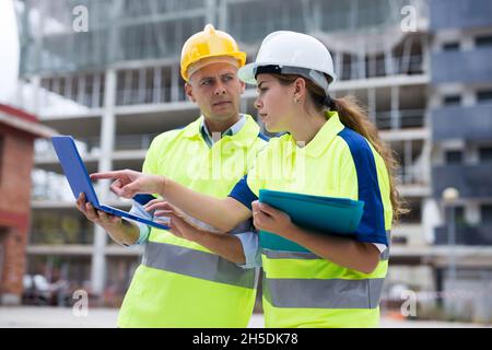 Two engineers are discussing an important project, holding a laptop and an estimate Stock Photo
