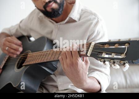 Cropped image of bearded man playing guitar and singing a song Stock Photo
