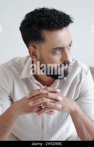 Pensive frowning bearded man in white shirt looking away Stock Photo