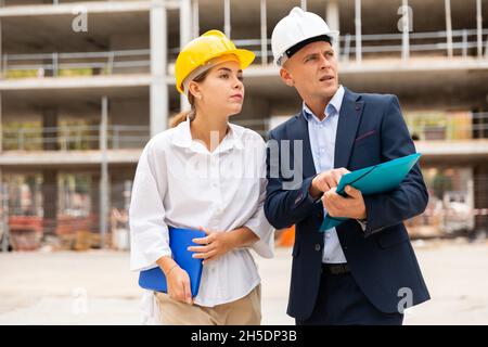 Two young successful architects on the construction site, discuss the construction plan Stock Photo