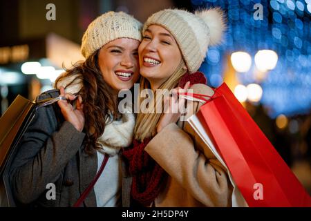 Portrait of happy women enjoying christmas fair and shopping together outdoors. Stock Photo