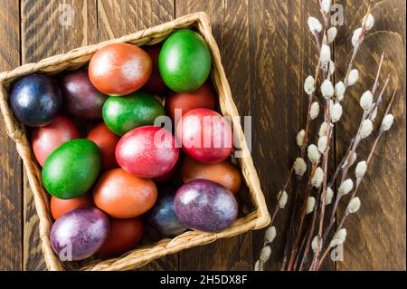 view from above of a wooden box with Easter colorful eggs and willow twigs. the concept of celebrating Easter Stock Photo