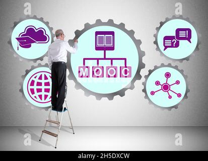 Man on a ladder drawing mooc concept on a wall Stock Photo