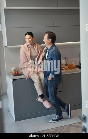 Jolly mature couple spending time in kitchen Stock Photo