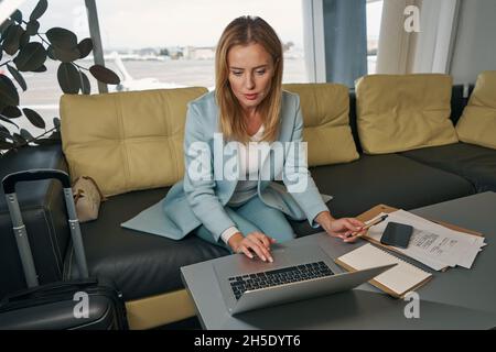 Female traveler sitting at desk before notebook computer Stock Photo
