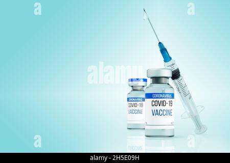 Two vials of coronavirus vaccine. The syringe rests on a glass bottle. A drop of medicine came out of the needle. Injection against the COVID-19 virus Stock Photo