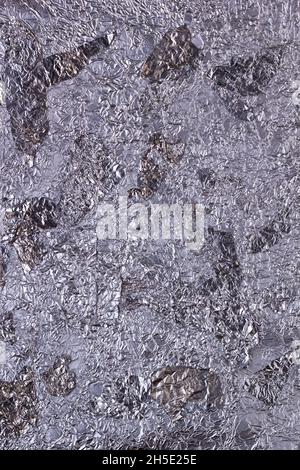 Shiny heavily wrinkled metal silver gray foil vertical texture background for design Stock Photo