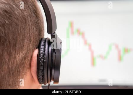 Close-up of a man with headphones looking at the monitor on red-green graphics, photos from the back Stock Photo