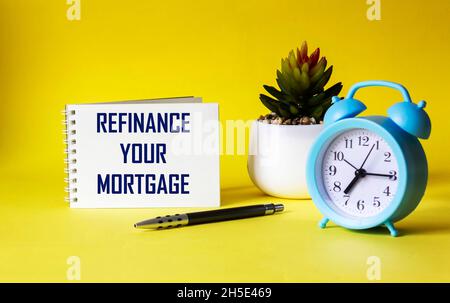 Refinance your mortgage, text on notepad and yellow background. Business concept Stock Photo