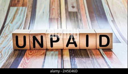 UNPAID word written on a wooden block. UNPAID text on striped background for your design, concepts. Stock Photo