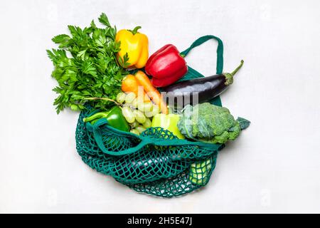 Eco friendly mesh shop bag with raw organic green vegetables isolated on white background Flat lay, top view Zero waste, plastic free concept. Stock Photo