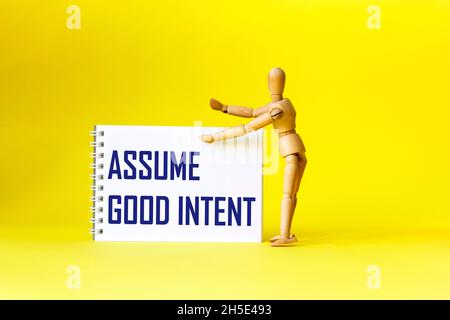 Assume Good Intent, inspirational quote on notepad with wooden doll, positivity concept Stock Photo