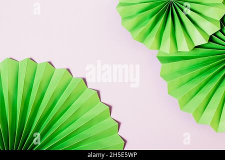 Colorful festive background of green paper fans on light purple Stock Photo