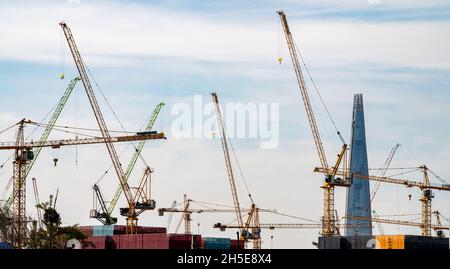 Panorama with many tower cranes in clear blue sky with clouds. Stock Photo
