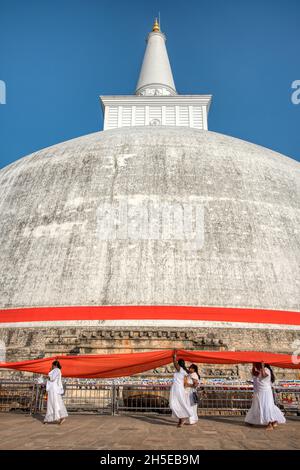 Anuradhapura, Sri Lanka - 13th January 2020: At a special ceremony an orange ribbon is wrapped around the Ruwanwelisaya Stupa by a procession of peopl Stock Photo