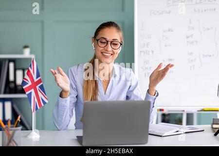 Distance education. Happy English teacher giving online lesson, gesturing and explaining rules, looking at laptop webcam Stock Photo