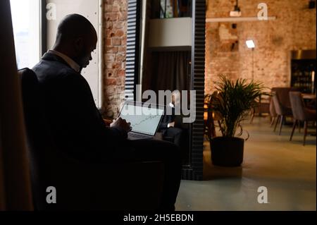 a young aspiring African-American investor works at a computer, analyzes the securities market Stock Photo