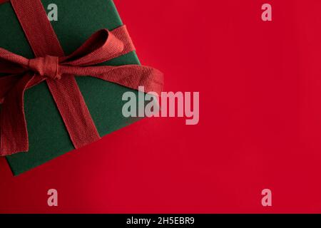 Festive christmas gift box present tied with a rustic ribbon and bow on a red background. Overhead view Stock Photo