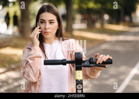 Female using phone during the break befour riding on e-scooter Stock Photo