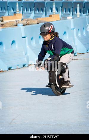 A young pre-teenage girl fearlessly rides on an Imotion electric unicycle in Flushing Meadows Corona Par in queens, New York City. Stock Photo