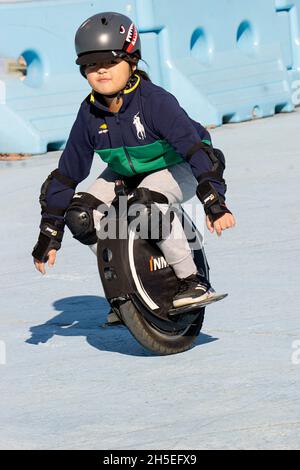 A young pre-teenage girl fearlessly rides on an Imotion electric unicycle in Flushing Meadows Corona Par in queens, New York City. Stock Photo