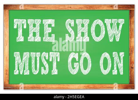THE SHOW MUST GO ON written on green wooden frame school blackboard Stock Photo