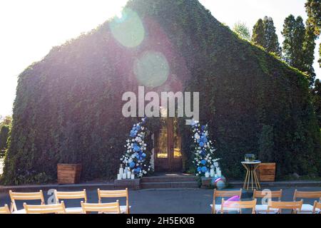 Wedding arch for the ceremony, decorated with fresh white roses, blue orchids and candles. Wedding decor. Soft selective focus. Stock Photo
