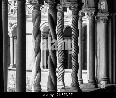 Black and white photo of curved decorated pillars sustaining arches in the interior patio of a medieval monastery in Italy Stock Photo