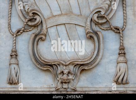 Close-up on Vatican´s coat-of arms carved on a marble wall showing in its bottom part a monstruous face sticking out the tongue Stock Photo