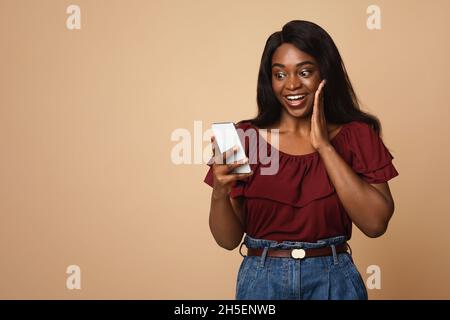 Emotional black woman using nice mobile app on smartphone Stock Photo