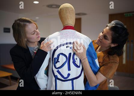 Rosalind Wyatt (right) examines a quote from cancer patient Laura Nuttall (left), which has been hand-stitched onto the back of one of three lab coats which have been made into a 'wearable work of art', and are on display at the Institute of Cancer Research in Sutton, south west London. British textile artist Rosalind Wyatt has transformed three lab coats with hand-stitched quotes, letters and illustrations from children and adults with rare and hard to treat cancers, raising awareness of 'cancers of unmet need'. Picture date: Tuesday November 9, 2021. Stock Photo