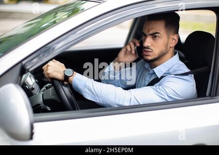 Angry arabic guy manager fighting on phone while driving auto Stock Photo