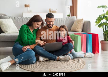 Happy Arab family using laptop in living room Stock Photo