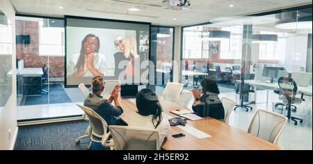 Global businesspeople clapping during a video conference. Group of creative businesspeople attending a virtual meeting with their partners in a boardr Stock Photo