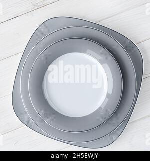 The modern classical porcelain set of plates stands on a white wooden table Stock Photo