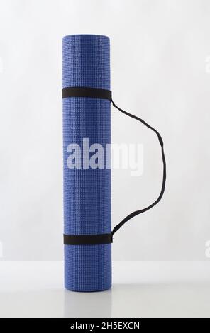 Rolled up blue yoga mat isolated on white background Stock Photo