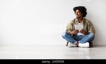 Online Offer. Cheerful Young Black Guy Holding Digital Tablet And Looking Aside Stock Photo