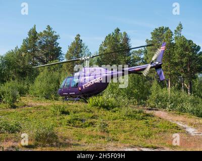 Jokkmokk, Norrbotten, Sweden, Agust 7, 2021: violet helicopter of Fiskflyg lands with supplies for Saltoluokta Fjallstation STF mountain lodge on Stock Photo