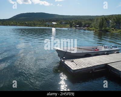 Saltoluokta, Norrbotten, Sweden, Agust 7, 2021: motor boat fasten at wooden pier in Saltoluokta saami village at Lule river, Lulealven lake with Stock Photo