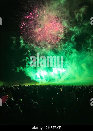 Firework display watched by a large crowd of people. Stock Photo