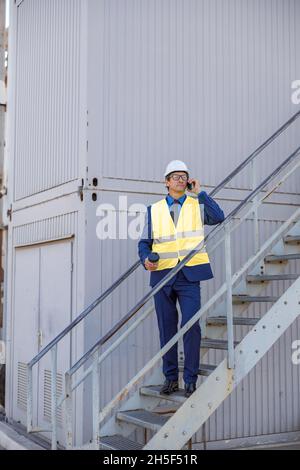 Male engineer standing on stairs and having phone conversation Stock Photo