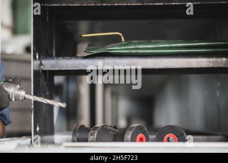 Worker with a drill drills a hole in the iron structure. Stock Photo