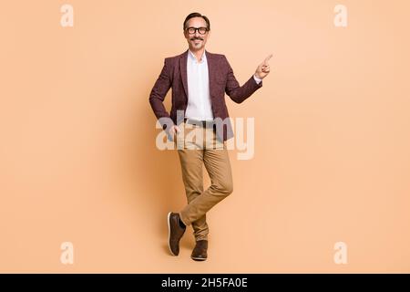 Full length body size view of attractive cheery man demonstrating copy space advert offer isolated over beige color background Stock Photo