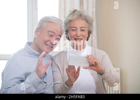 Happy elderly couple having video call on their cell phone Stock Photo
