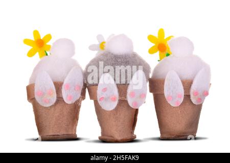 Easter bunnies bottoms up with fluffy tails and a flower leaning into some pots. Isolated on a white background. Seasonal background for spring Stock Photo