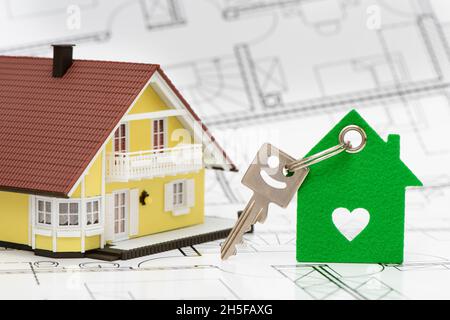 model house with key standing on architectural plan Stock Photo